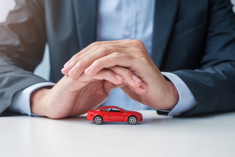 Businessman hand cover or protection red car toy on table. Car i